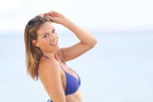 Woman in blue bikini enjoys her new physique on the beach