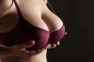 Woman with large breasts has to hold up her breasts even while wearing a bra.