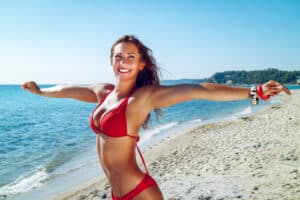 Young woman in red bikini enjoys running on the beach