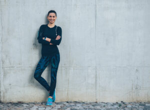 Woman in athleisure clothing is pleased with her figure.
