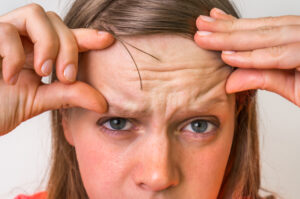 Woman in her 40s is not pleased with the appearance of forehead wrinkles.